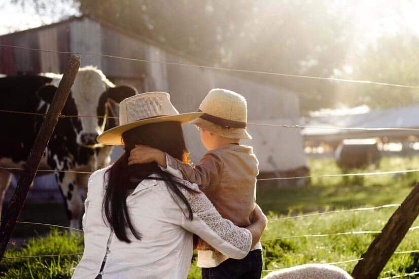 Une mère et son fils regardant une vache dans une ferme.