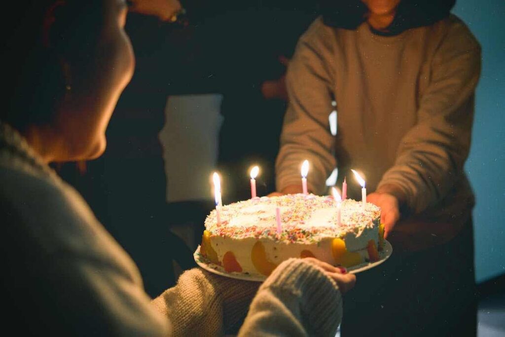 Une femme soufflant sur les bougies d'un gateau d'anniversaire, vœux de joyeux anniversaire