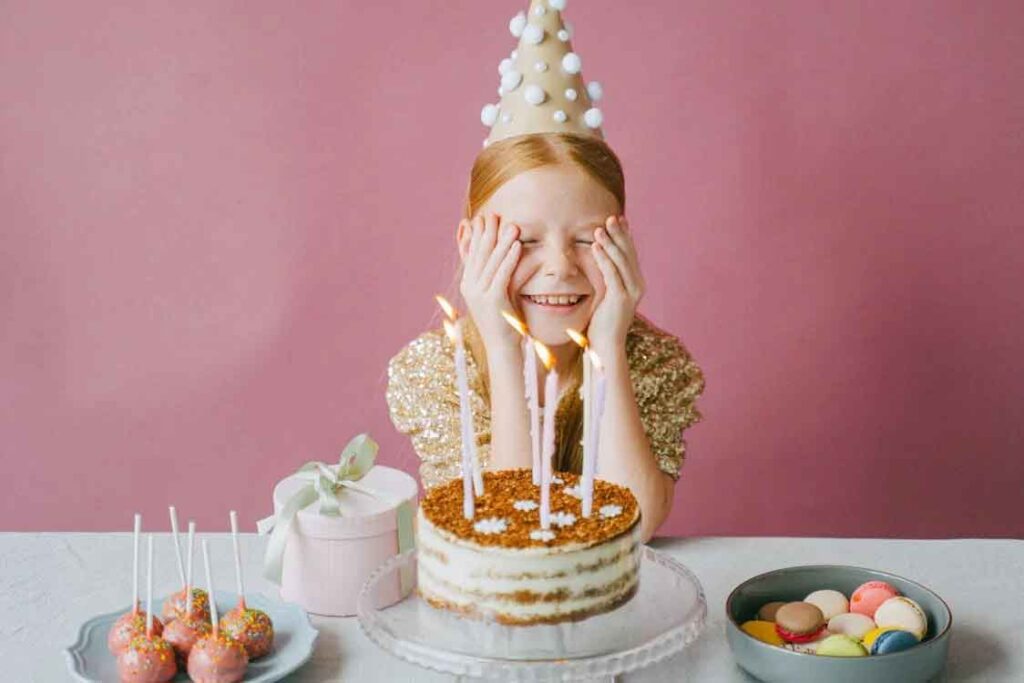 Jeune fille toute émut avant de souffler sur les bougies du gateau d'anniversaire.