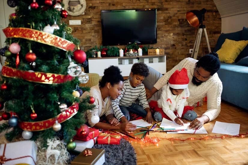 En passant une journée d'activités de Noël à la maison, la famille de noires créative colorie sur papier.