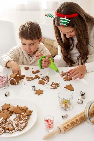 frère et sœur décorant des biscuits de Noël