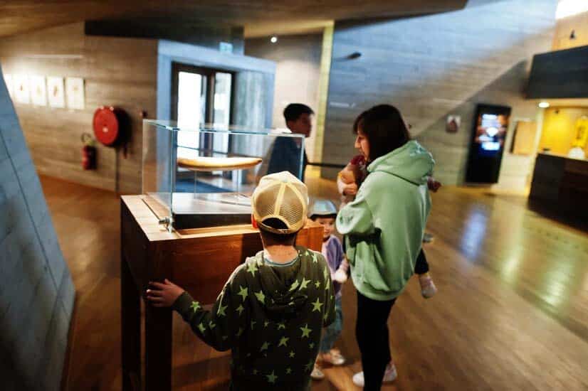 Une mère avec trois enfants visitant les expositions dans les salles de musée.