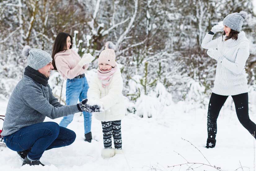 Activités de Noël : famille jouant aux boules de neige dans la campagne