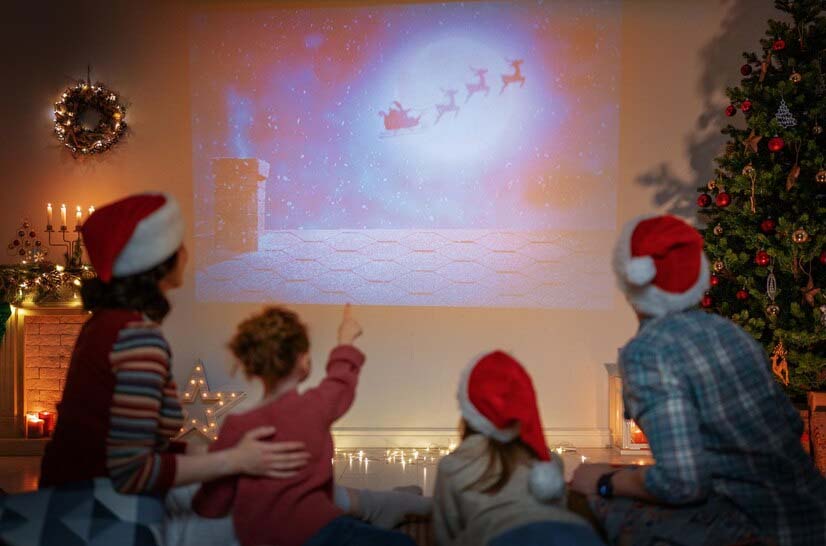 une femme et trois enfants regardent un film de Noël.