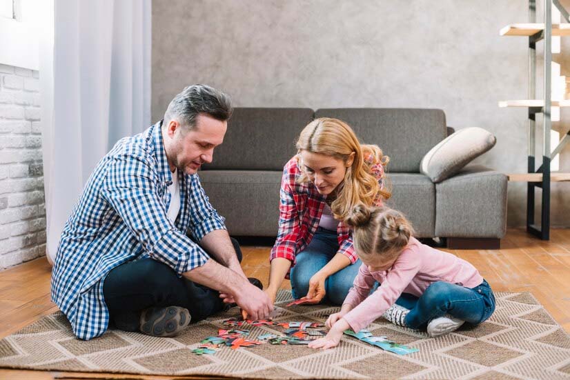 couple jouant des pièces de puzzle avec leur fille à la maison.