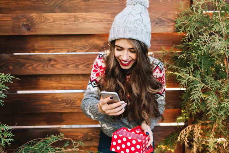 Une jeune femme lisant un sms de vœux de Noël