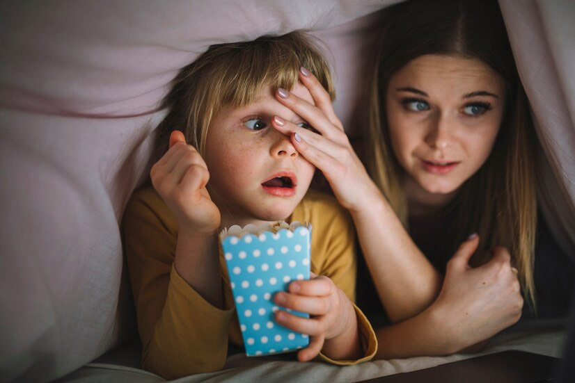 un jeune garçon et sa mère regardent un film.